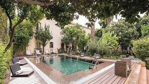 A swimming pool with lounge chairs and a wooden deck. - Hospes Palacio del Bailío, a Member of Design Hotels (Córdoba)