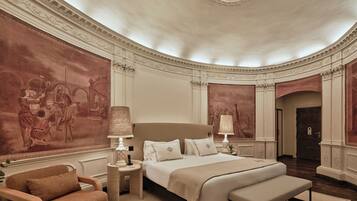 A luxurious bedroom with a large bed, a chaise lounge, and a mural on the wall.