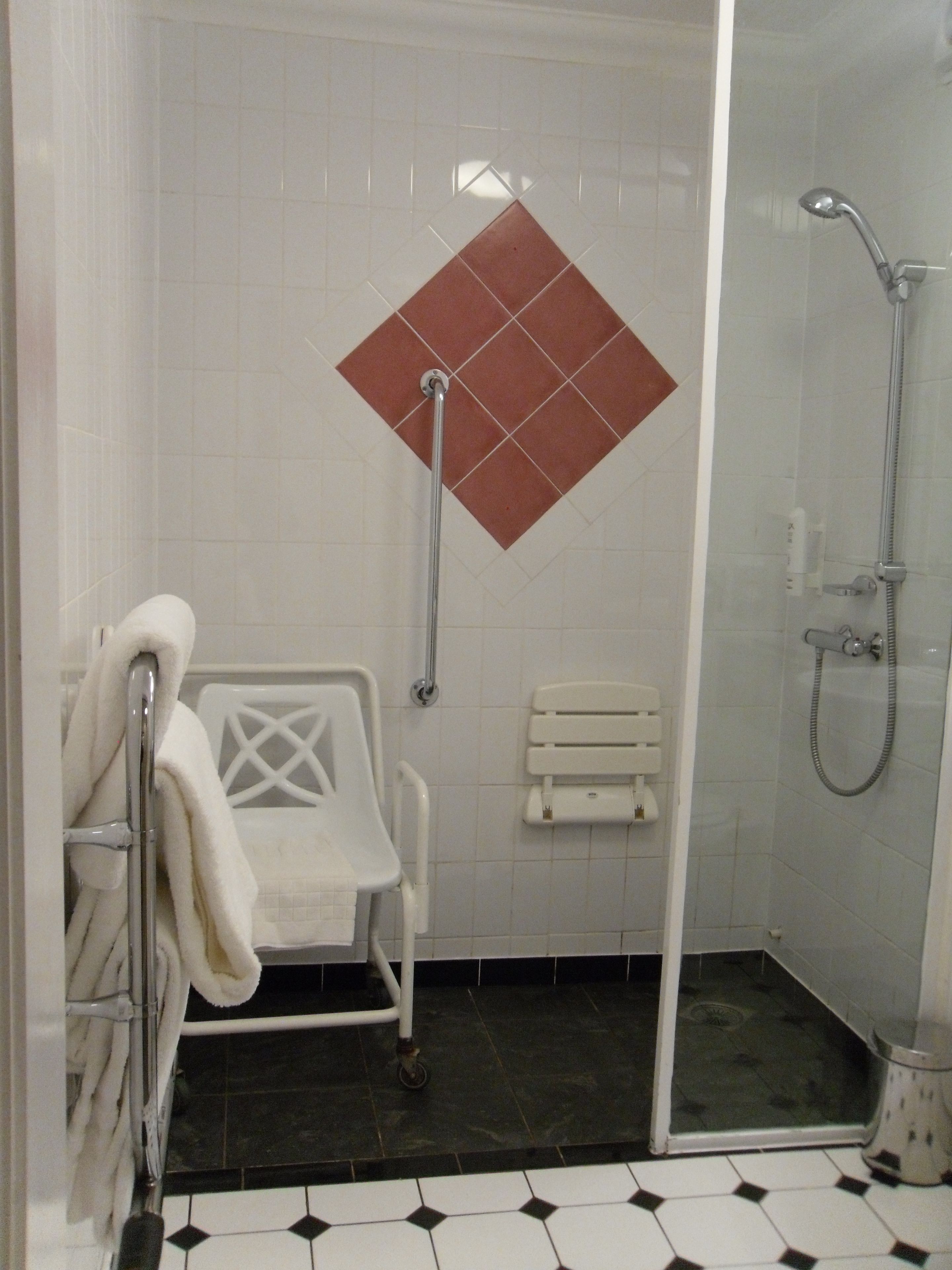 Et badeværelse med bruser, badekar, toilet og håndvask, alt i hvidt.