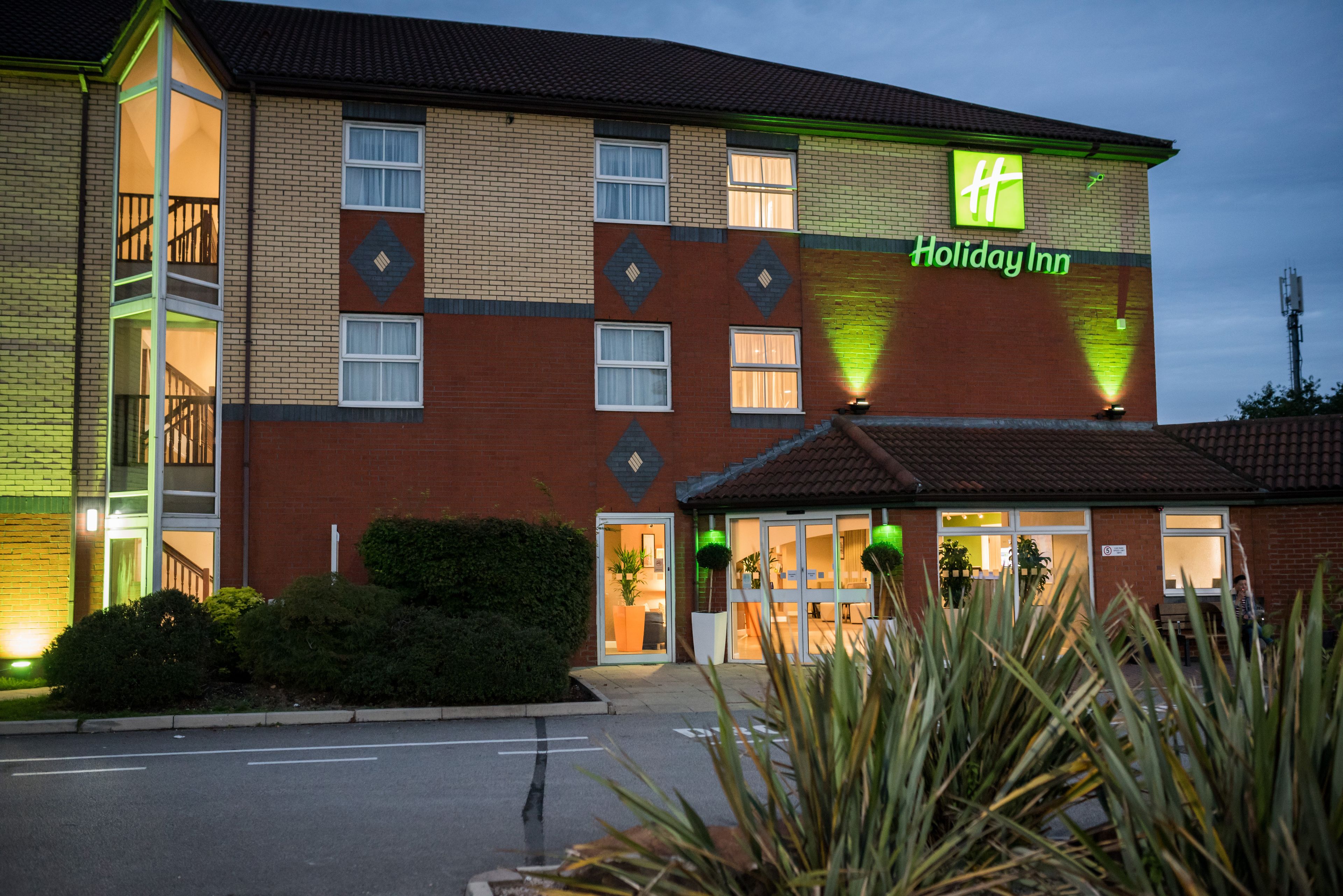 A Holiday Inn hotel with a brick facade, multiple windows, and a visible entrance.