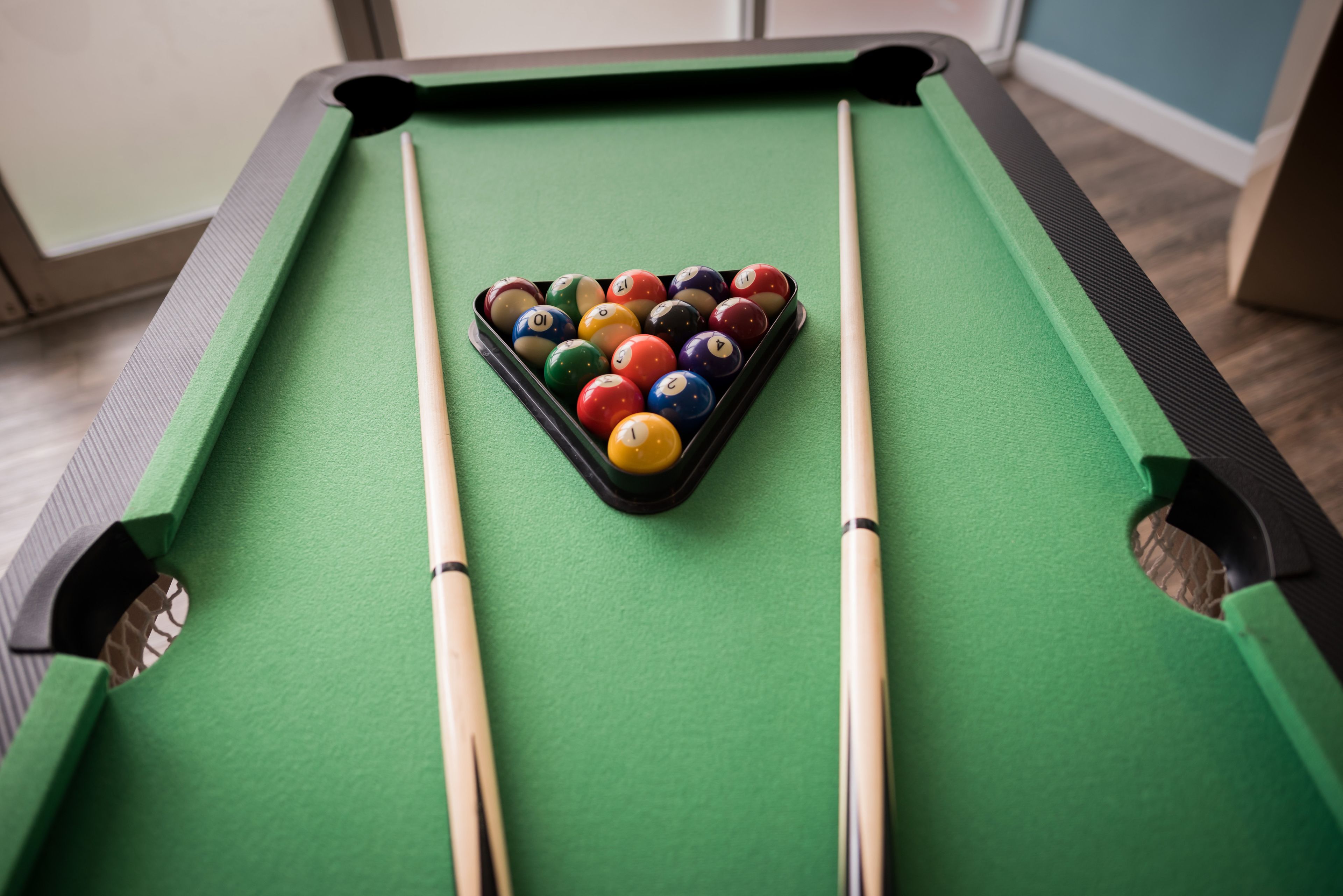 Une table de billard avec un triangle de billes et deux queues de billard.