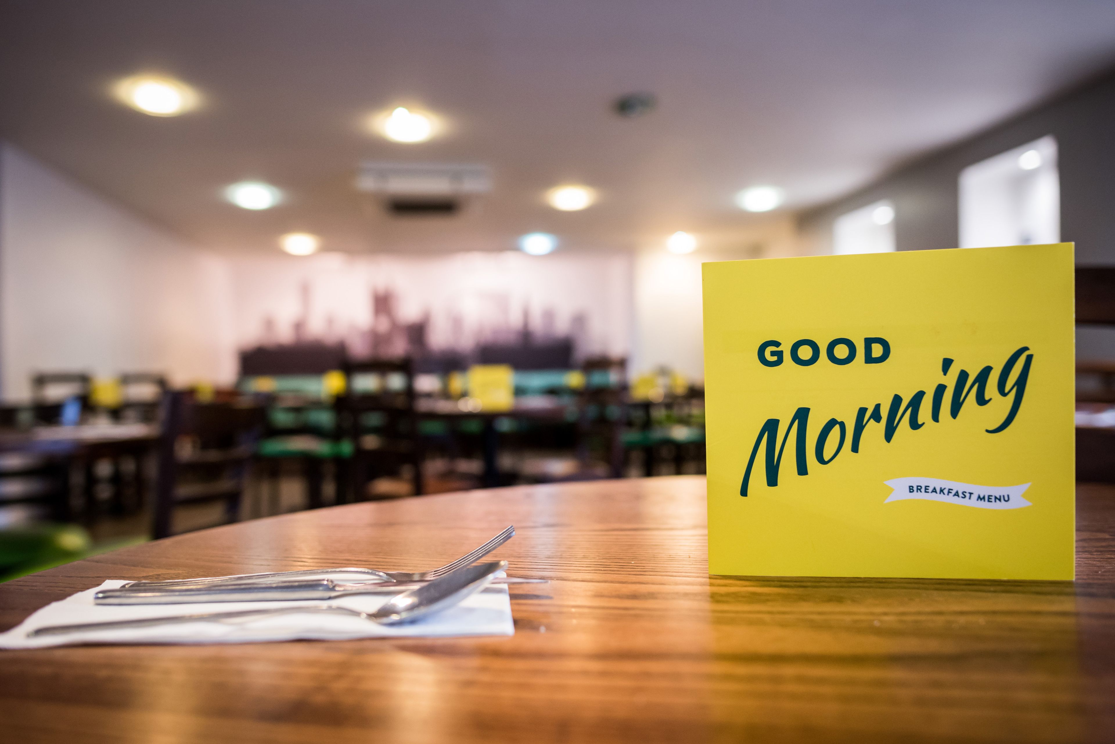 A restaurant table with a yellow sign reading "GOOD MORNING" and a breakfast menu.