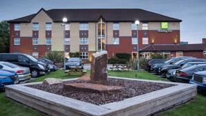 A Holiday Inn hotel with a parking lot, a stone fountain, and a well-maintained lawn. - Holiday Inn Manchester West by IHG (Salford)