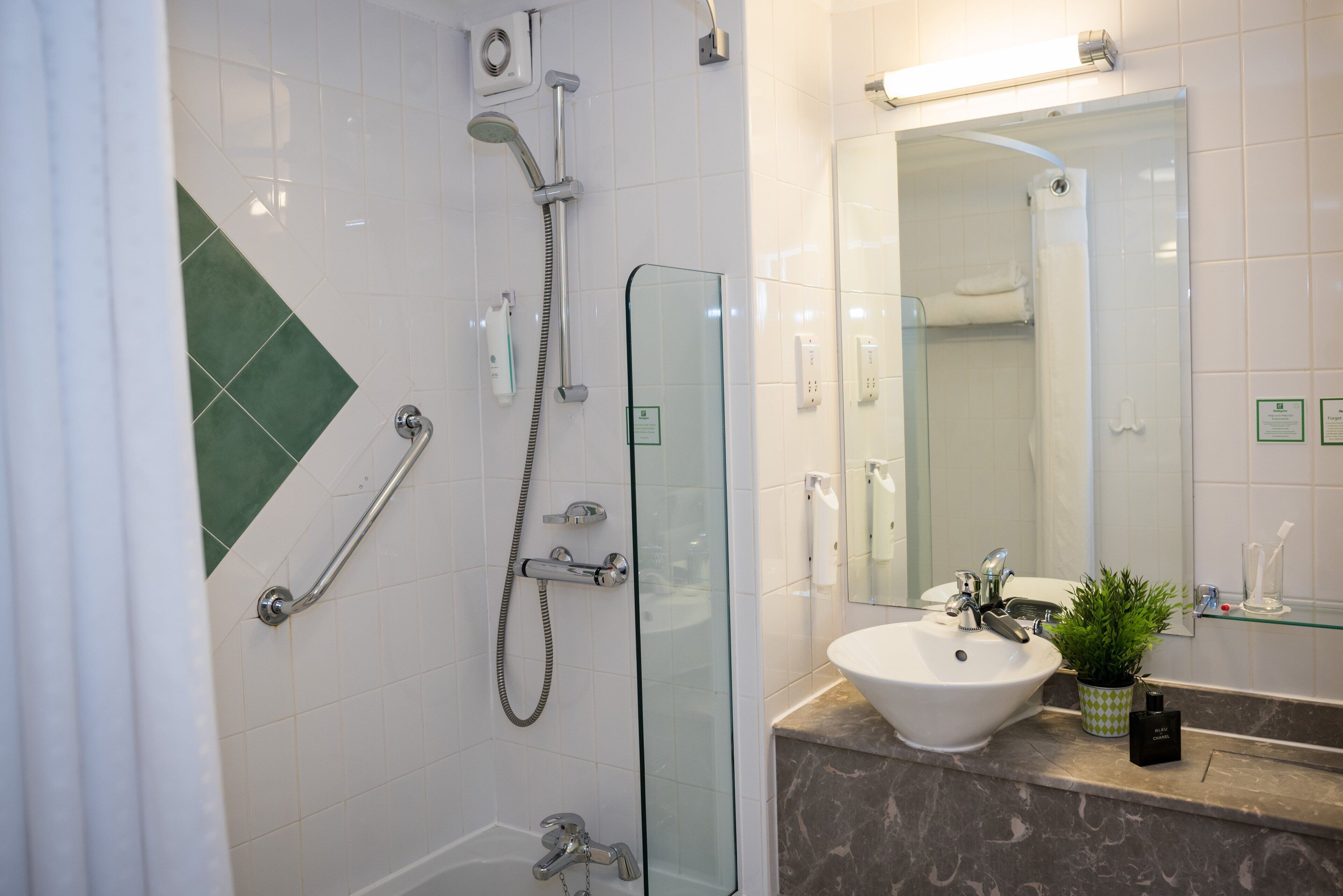 A modern bathroom with a glass shower enclosure, a white sink, and a marble countertop.
