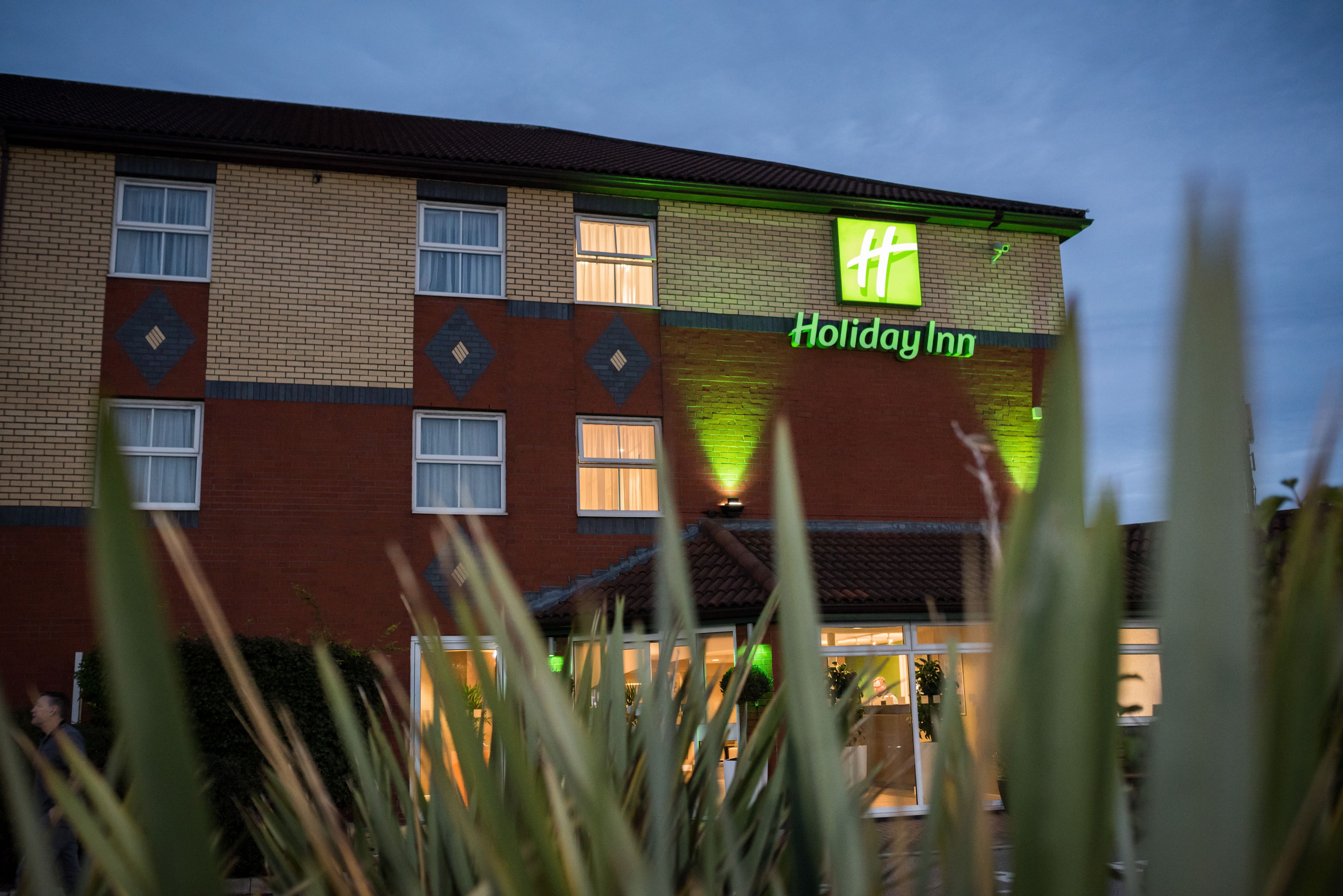 A Holiday Inn hotel with a brick facade and a green sign.