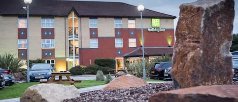 Un hotel Holiday Inn con fachada de ladrillo, múltiples ventanas y una entrada bien iluminada.