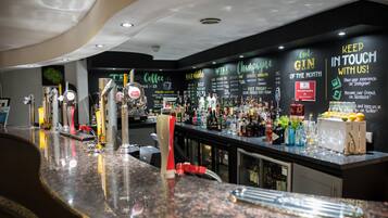 Een bar met een gepolijst granieten aanrecht, verschillende flessen en een keuze aan glazen.