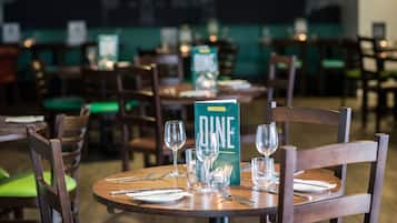 A restaurant setting with tables set for dining, chairs, and a menu stand.