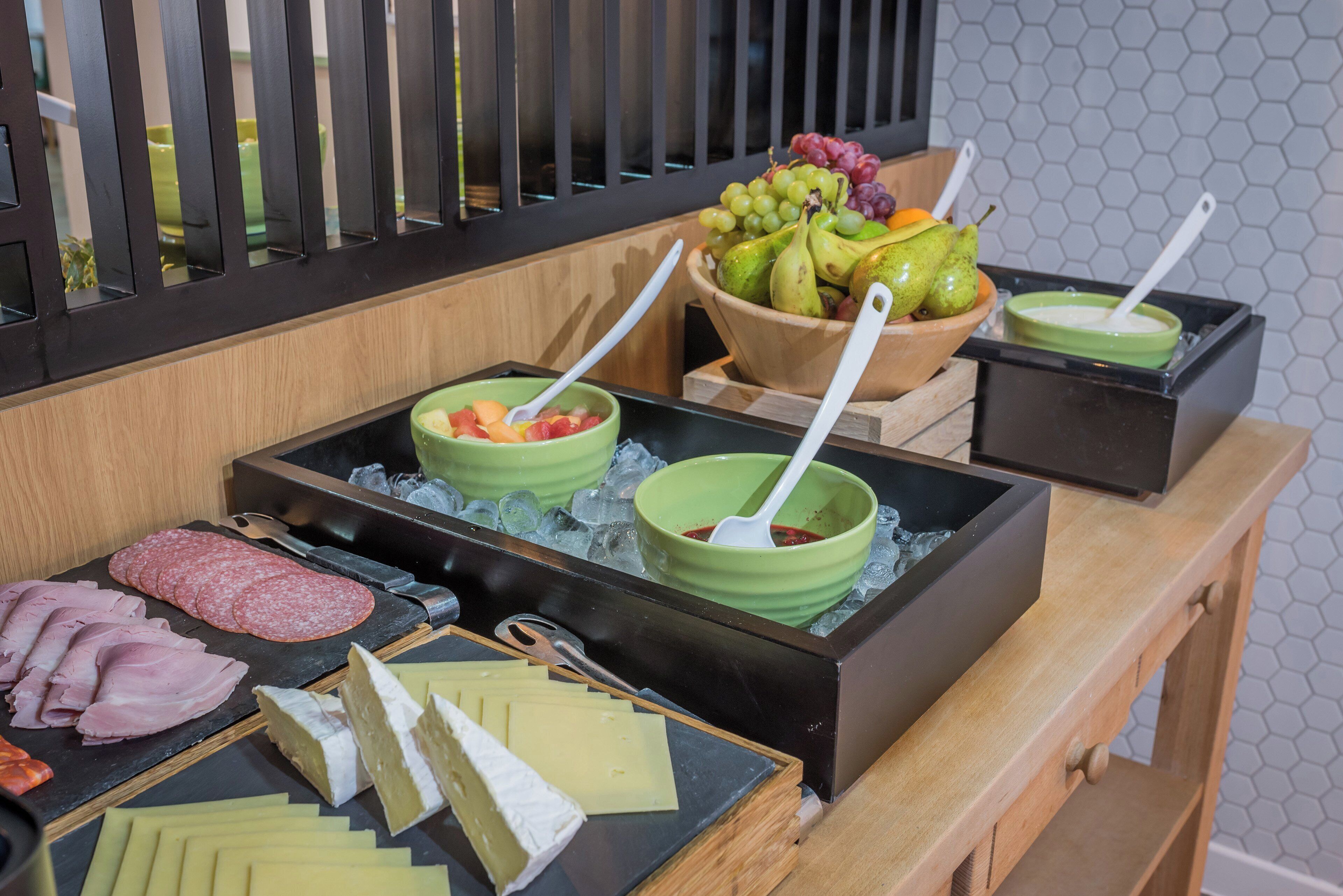 A buffet with various food items including meats, cheeses, fruits, and vegetables.