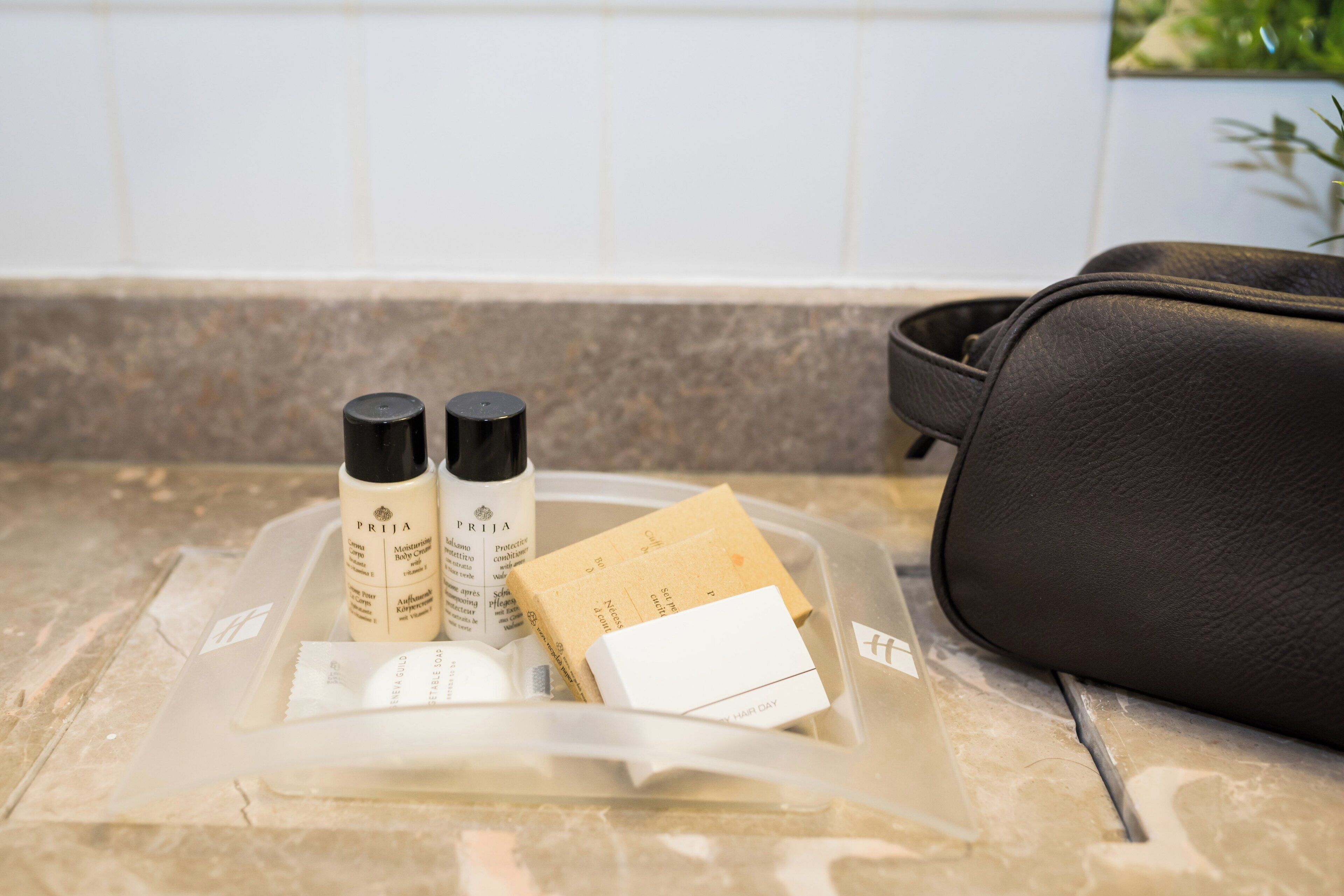 Un meuble-lavabo de salle de bain avec des articles de toilette et un sac en cuir noir.