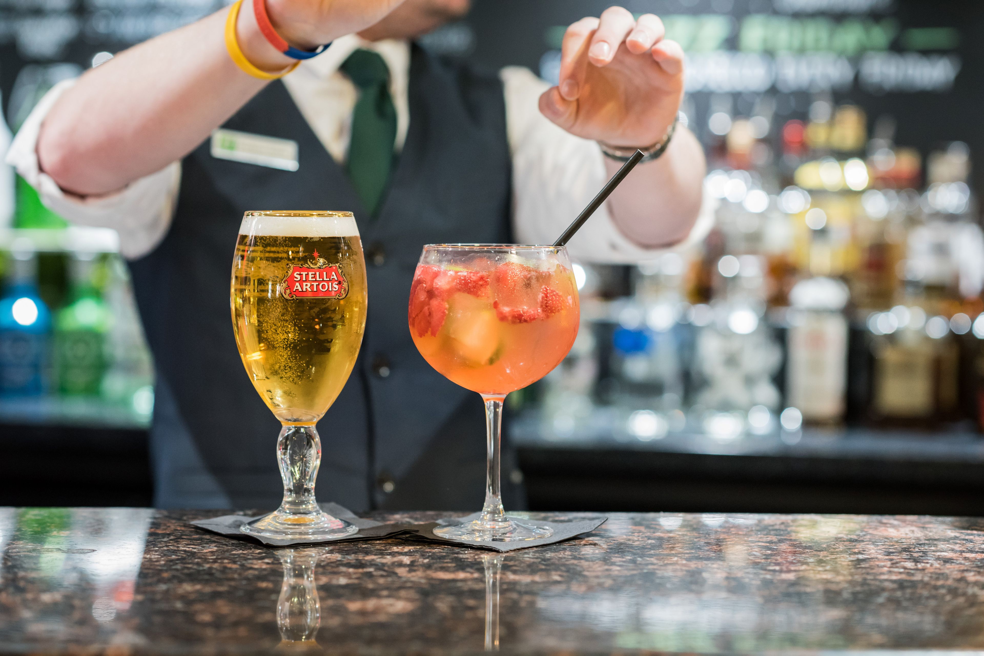 Twee cocktails op een barkruk met een vage achtergrond van flessen.