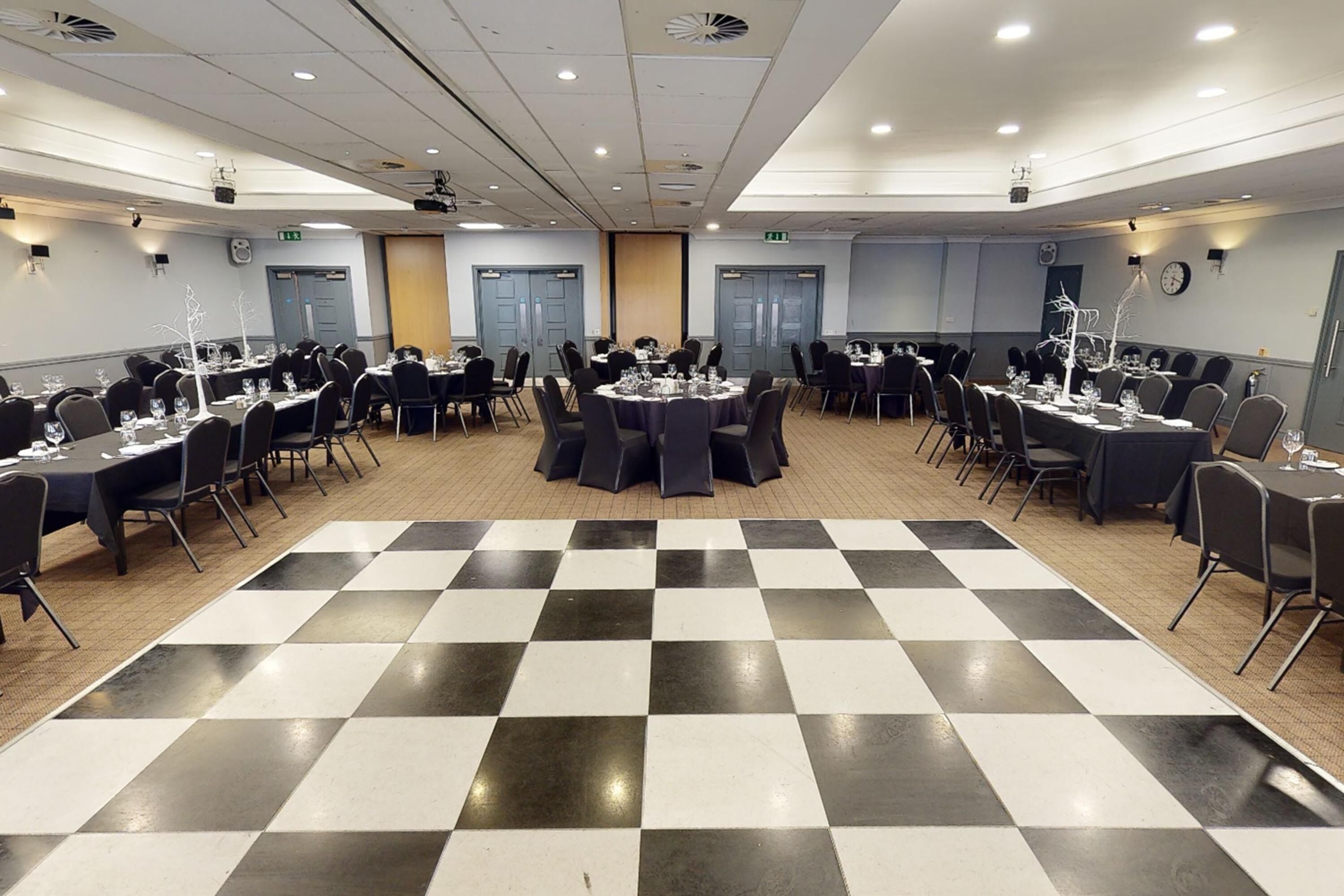 A conference room with round tables, chairs, and a checkered floor.