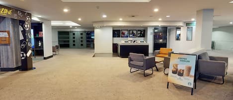 A spacious lobby with a reception desk, seating area, and a coffee cooler sign.