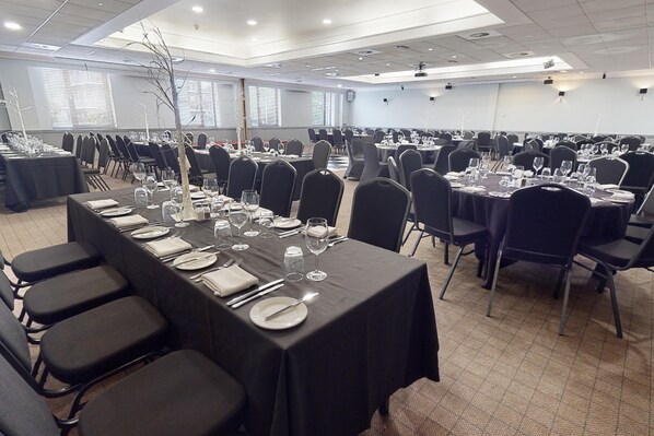 A conference room with multiple tables set for dining, equipped with chairs and tables.