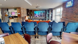 Eine moderne Bar mit blauen Stühlen, einem Fernseher und einem leuchtenden Bud Light-Schild.