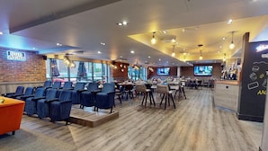 Ein modernes Restaurant mit Backsteinwand, Holzboden und verschiedenen Sitzgelegenheiten, darunter Tische und Stühle.
