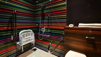 A bathroom with a modern design, featuring a shower with a handheld showerhead and a glass-enclosed toilet.
