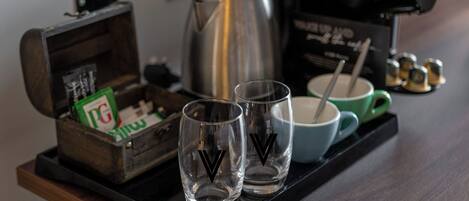 A tray with two glasses, a coffee pot, a box of PG cigarettes, and a mug on a wooden table.