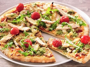 A pizza with various toppings and a cherry tomato garnish.