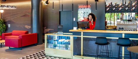 Un moderno espacio de bar con barra, asientos y una vitrina de vidrio.