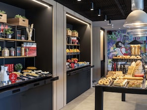 Interior de café moderno com balcão exibindo doces e parede com arte de graffiti.