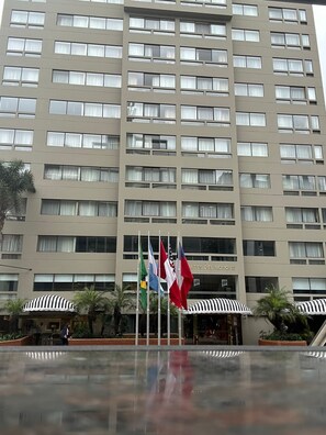 A multi-story hotel building with a flat facade, numerous windows, and a sign indicating it is a hotel. - Suites del Bosque Hotel (Lima)