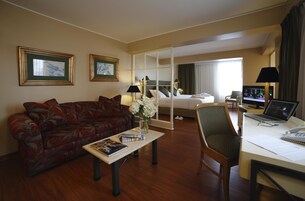 Una habitación de hotel con un sofá, un escritorio con una computadora portátil, una cama y un televisor.