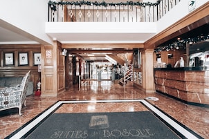 Un vestíbulo de hotel con una recepción, una escalera y un felpudo con el nombre del hotel.