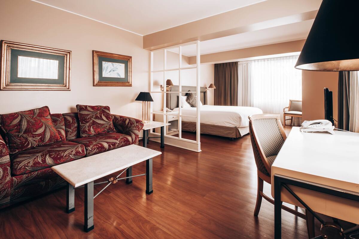 A hotel room with a sofa, a bed, a desk, and a chair.