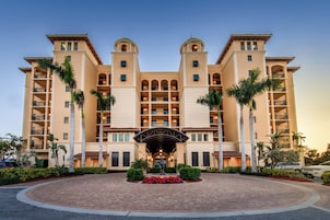 A multi-story hotel with a central courtyard, palm trees, and a fountain.