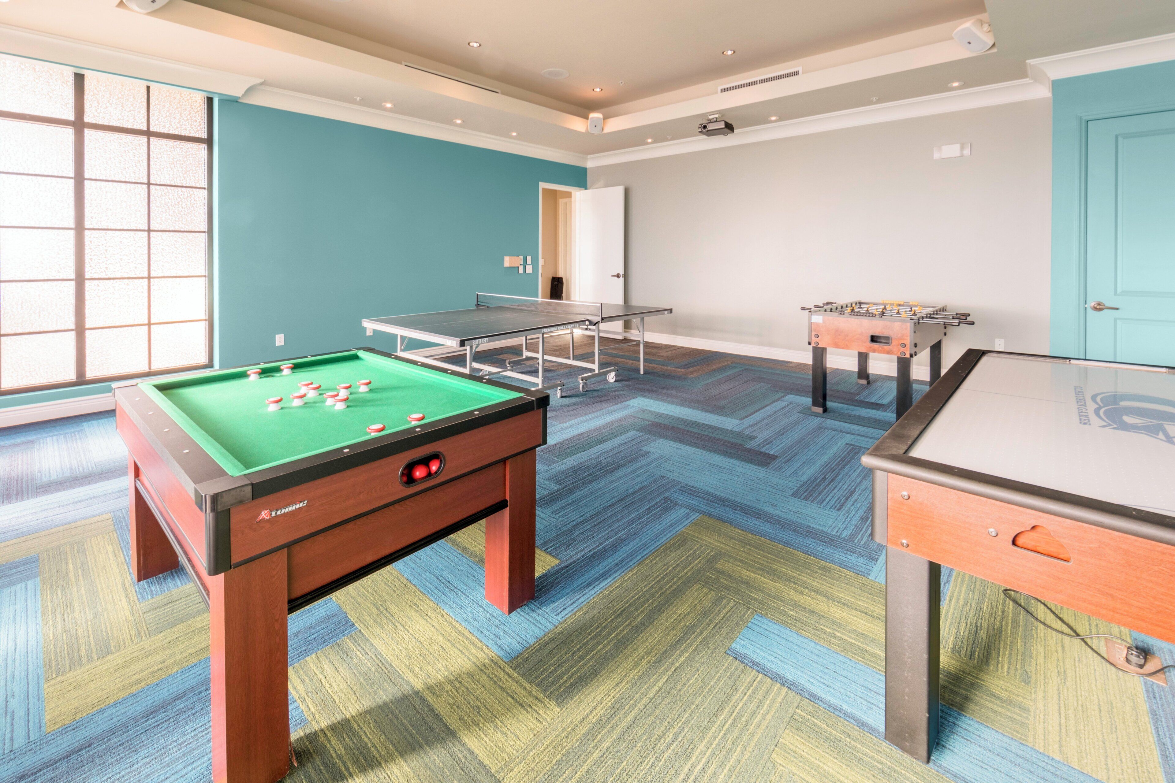 Una stanza con tavolo da biliardo, tavolo da calcio e tavolo da ping pong.