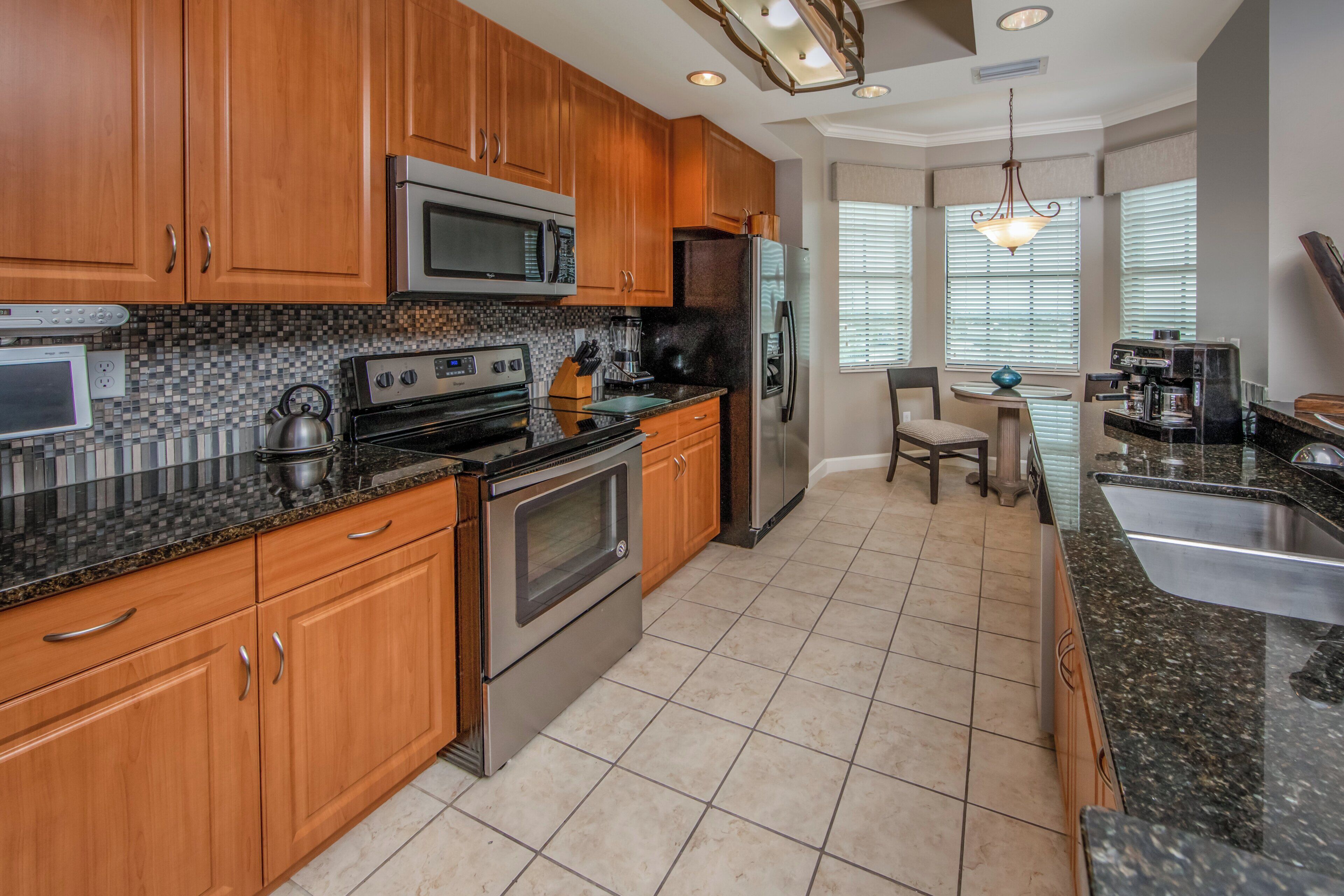 A kitchen with wooden cabinets, stainless steel appliances, a tiled backsplash, and a dining area with a table and chairs.