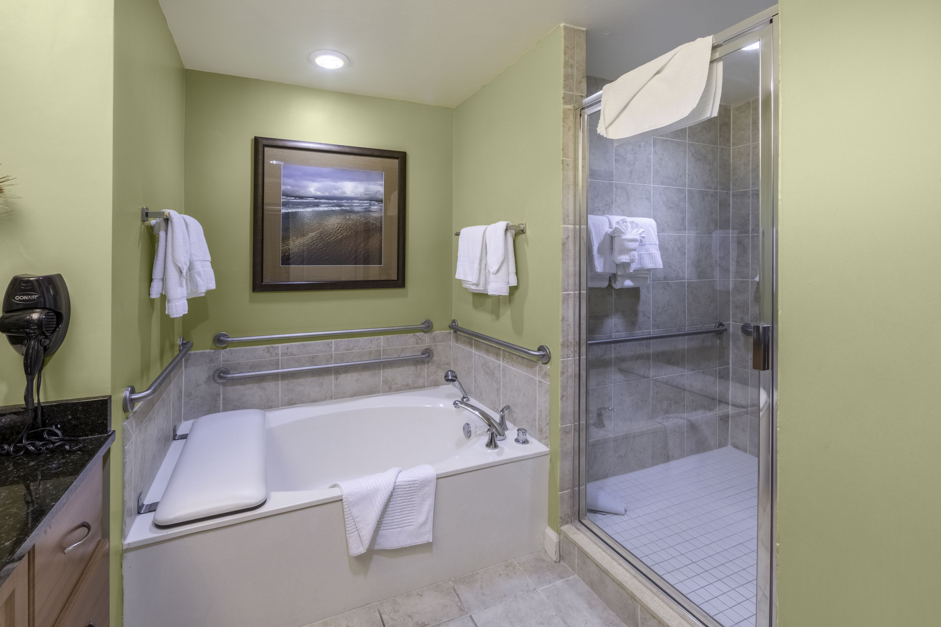 A bathroom with a bathtub, a shower, and a framed picture on the wall.