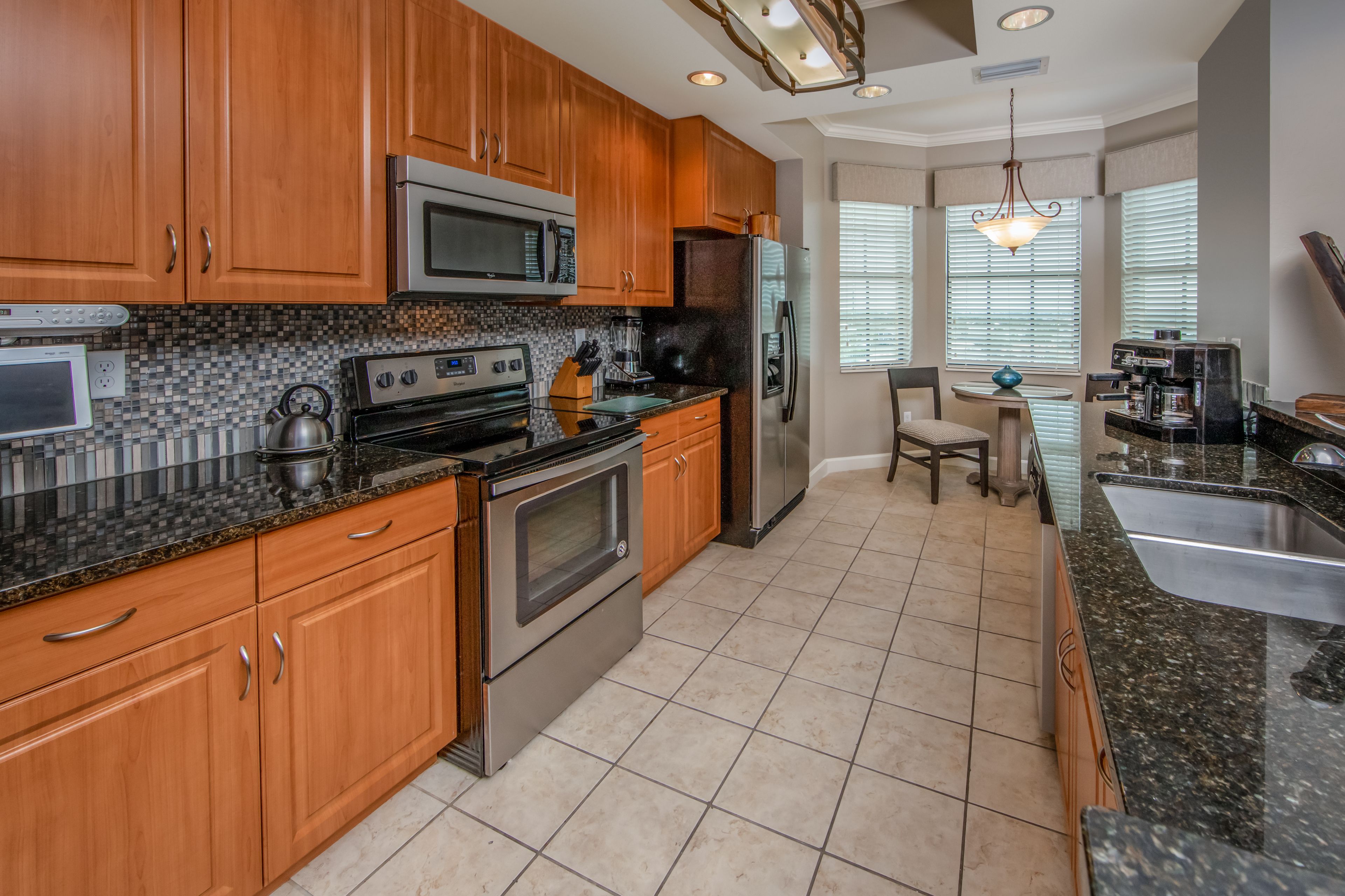 A modern kitchen with wooden cabinets, stainless steel appliances, and a granite countertop.