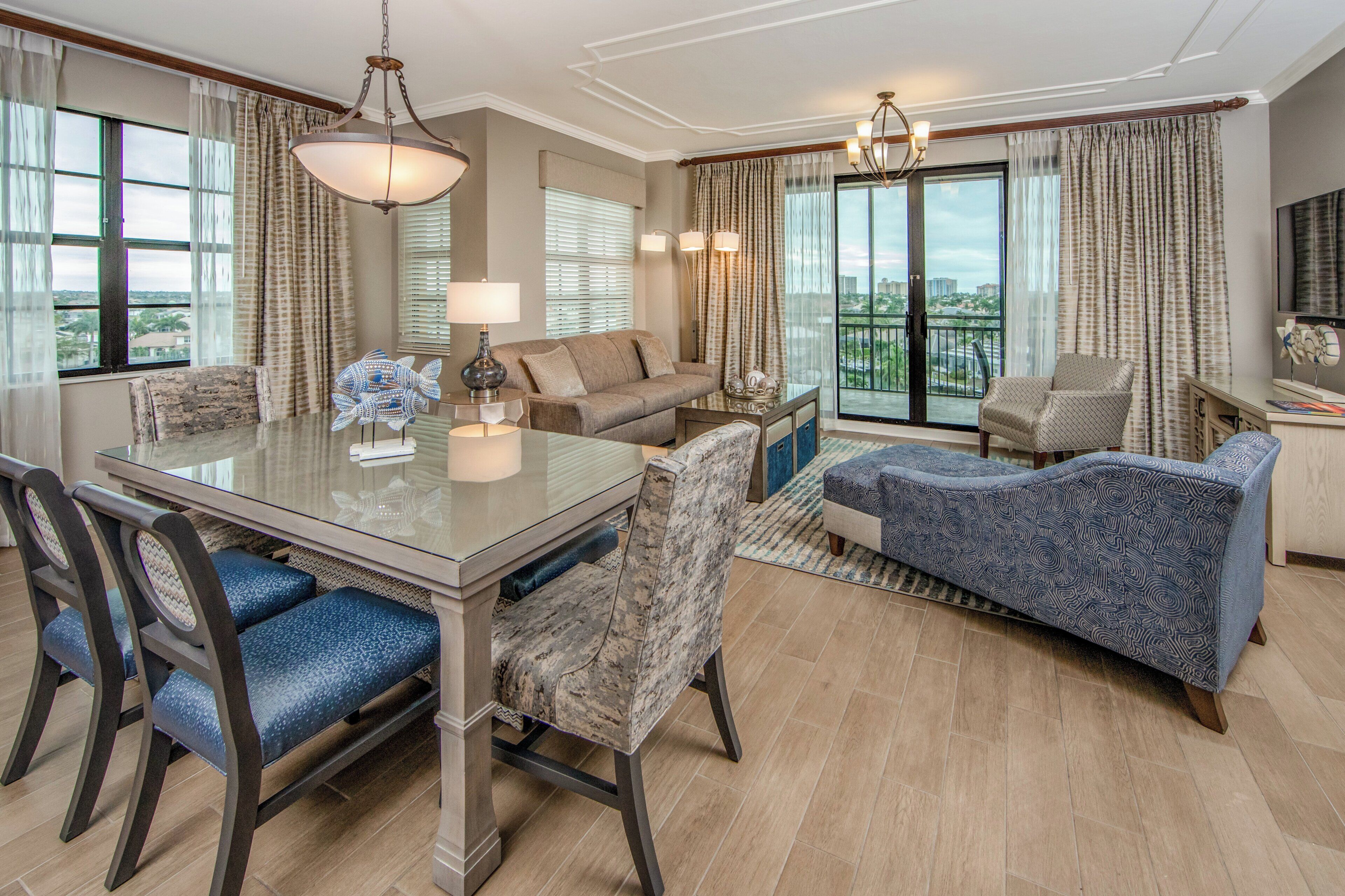 Een ruime woonkamer met een eettafel, stoelen, banken en een groot raam met uitzicht op de skyline.