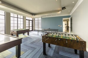 A room with a foosball table, pool table, and ping pong table, with large windows and a view of the outside. - Holiday Inn Club Vacations Sunset Cove Resort by IHG (Marco Island)