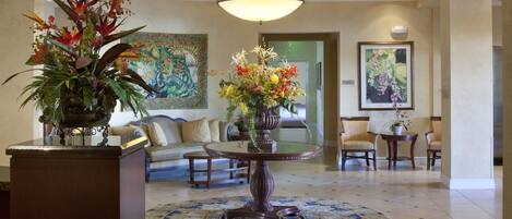 A lobby with a round table, sofas, chairs, and a large chandelier.