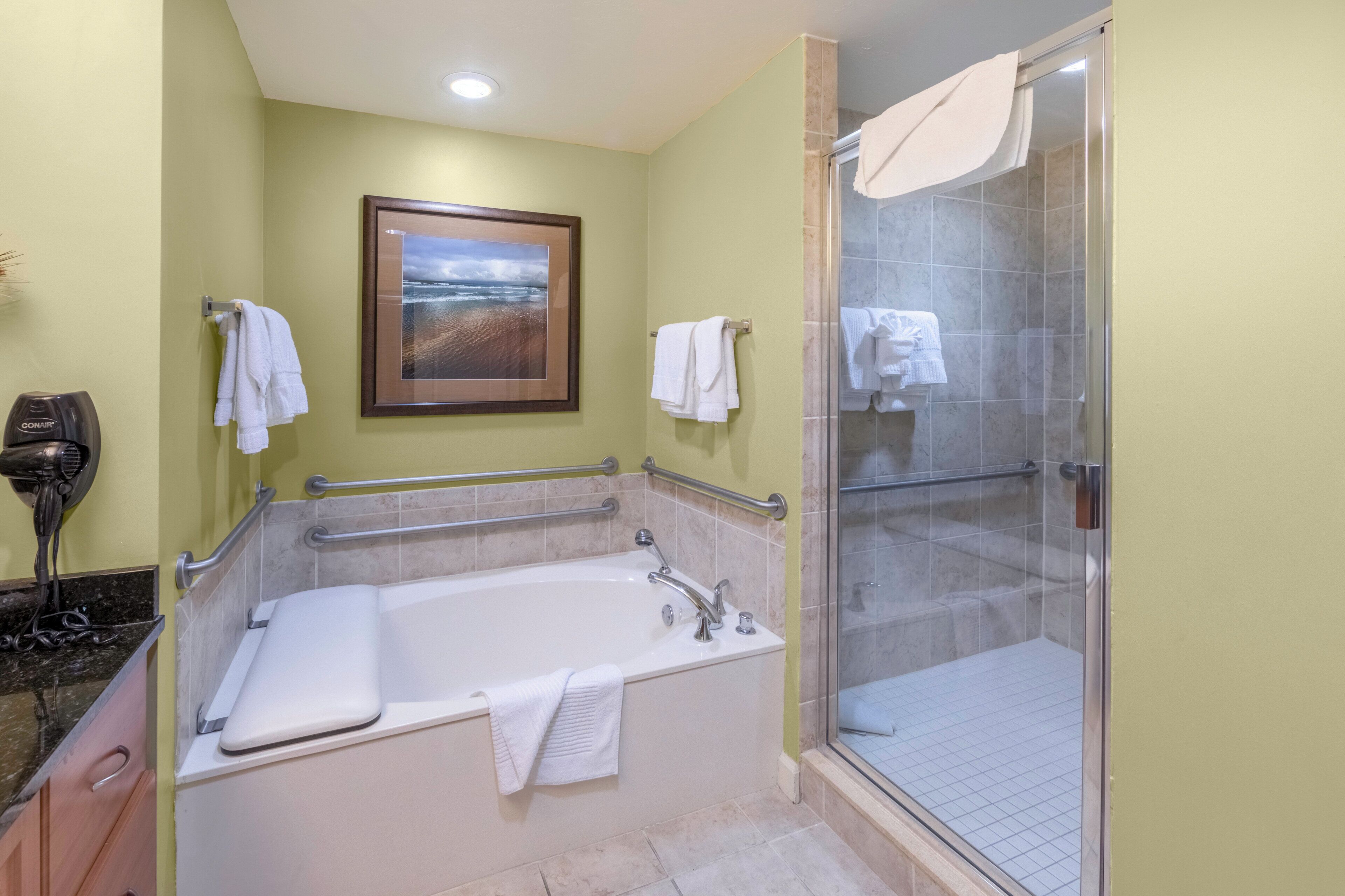 A bathroom with a bathtub, shower, and a framed picture on the wall.