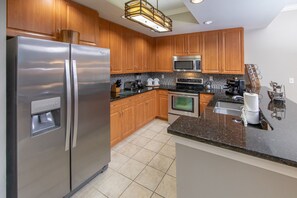 A modern kitchen with wooden cabinets, stainless steel appliances, and a granite countertop. - Holiday Inn Club Vacations Sunset Cove Resort by IHG (Marco Island)