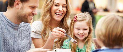 A family dining at a table with cake and coffee.