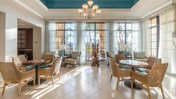 A spacious dining area with wicker furniture, large windows, and a blue ceiling.