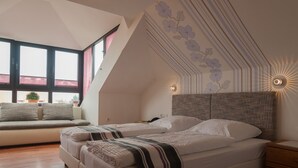Ein Schlafzimmer mit zwei Betten, einem Schlafsofa, einem Nachttisch und einer wandmontierten Lampe.