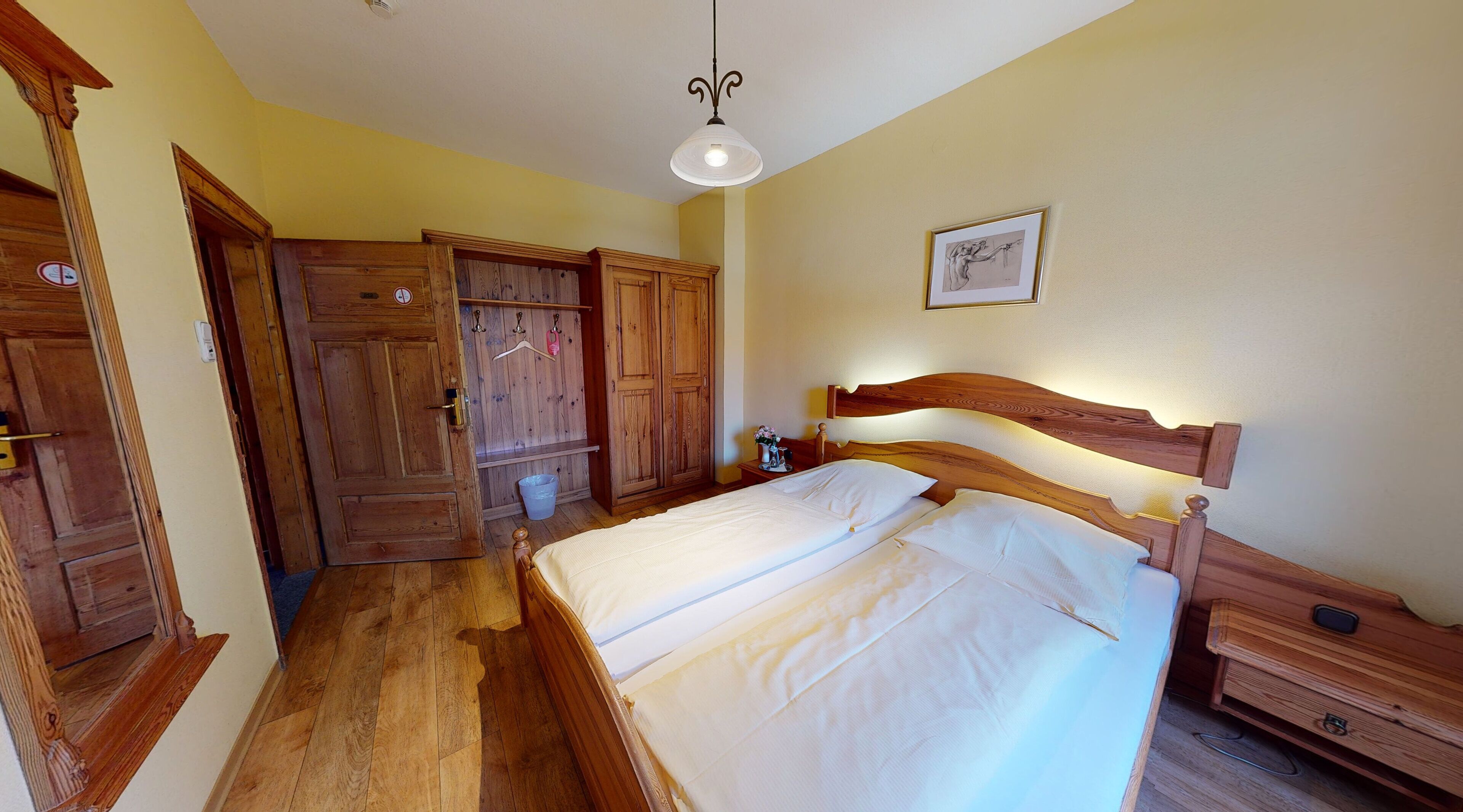 Un dormitorio con cama de madera, mesita de noche, armario de madera y lámpara colgante.