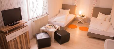 Une chambre d’hôtel comprenant un lit, un bureau avec un ordinateur, une chaise, une petite table et un radiateur.