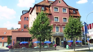 Ein Hotel mit roter Fassade, zahlreichen Fenstern und einem Schild, das es als Hotel und Restaurant kennzeichnet.