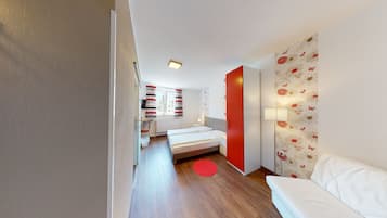 A modern bedroom with a bed, bedside table, and a red accent wall.