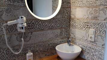 A bathroom with a wooden vanity, a white sink, and a round mirror.
