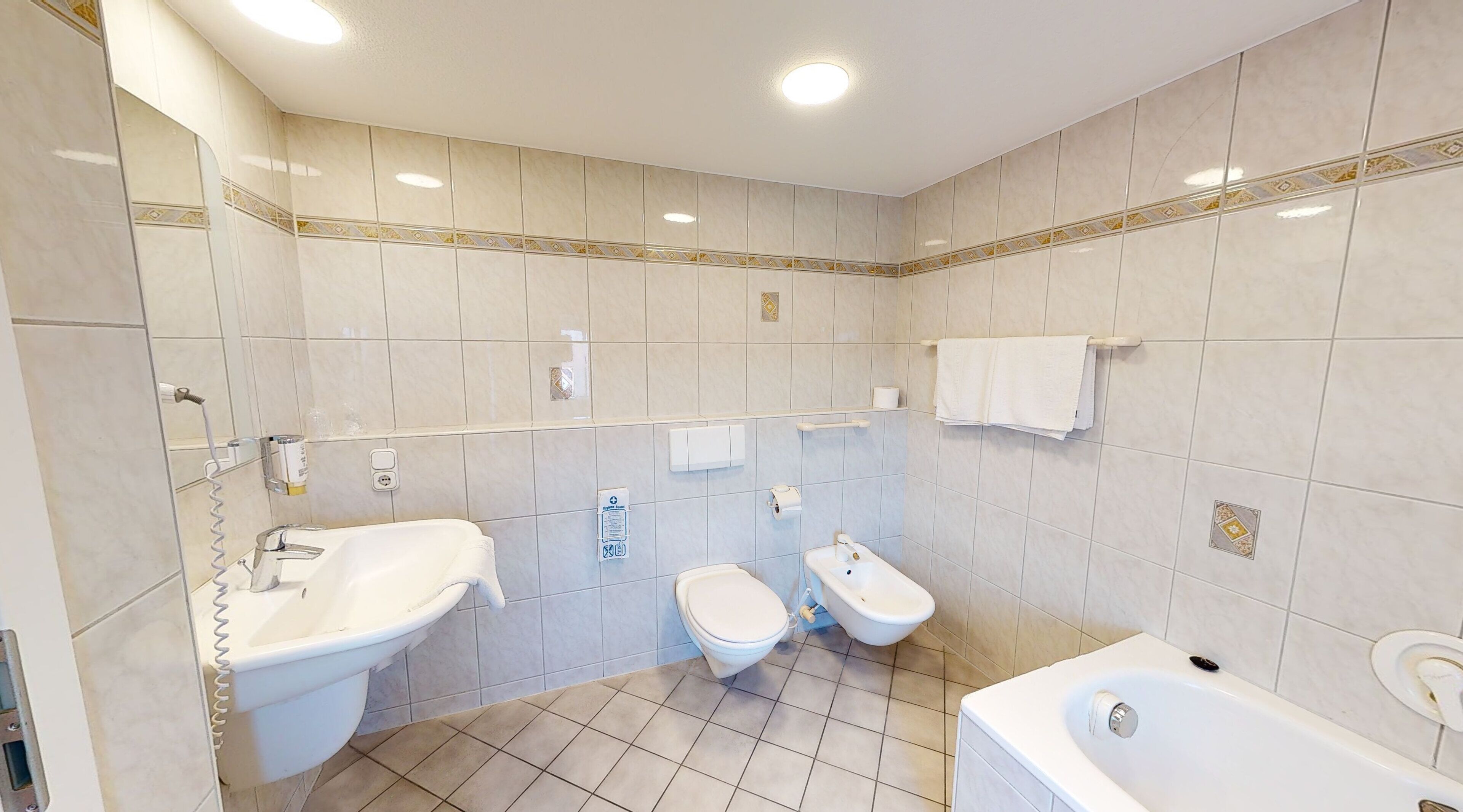 Une salle de bain moderne avec deux lavabos, des toilettes, un bidet et une baignoire.