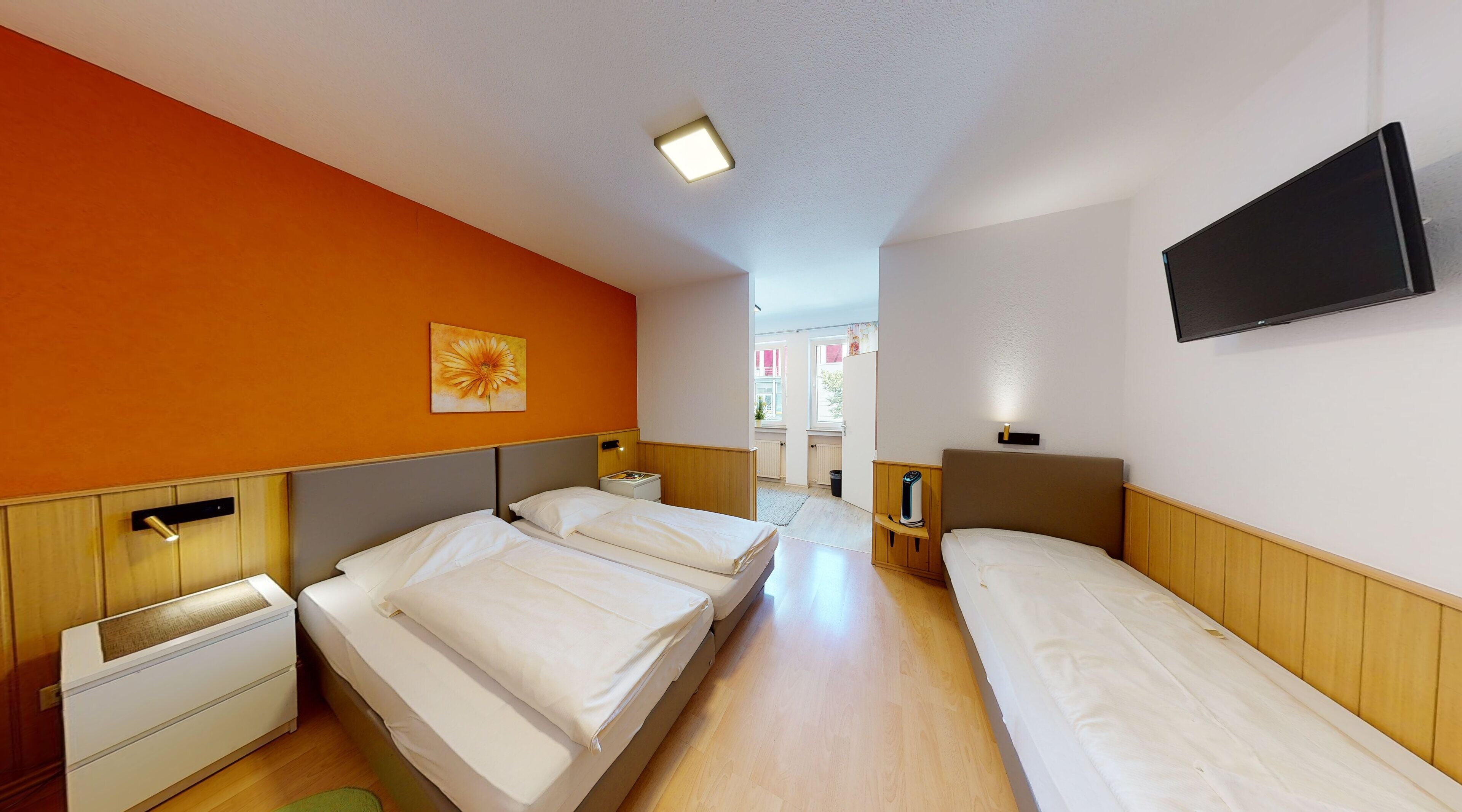 Habitación de hotel con dos camas, un televisor de pantalla plana y un cuadro en la pared.