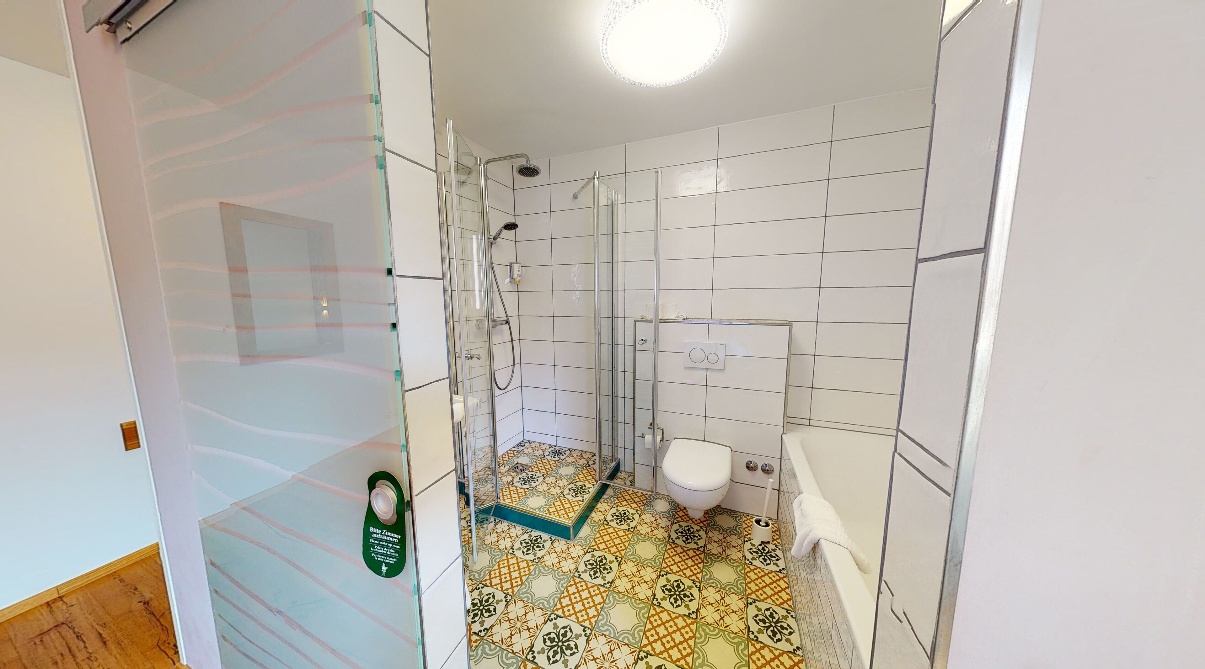 Une salle de bain avec douche, toilettes et carrelage au sol.